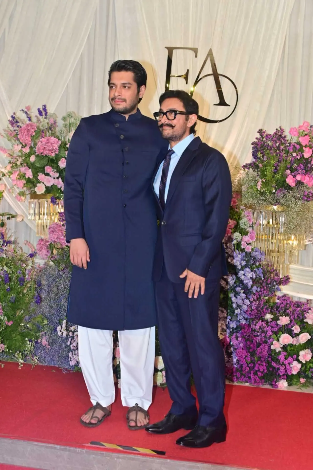 <p><span class="hover:entity-accent entity-underline inline cursor-pointer align-baseline"><span class="whitespace-normal">Aamir Khan</span></span> attended the wedding reception with his son <span class="hover:entity-accent entity-underline inline cursor-pointer align-baseline"><span class="whitespace-normal">Junaid Khan</span></span>. The actor looked sharp in a classic navy blue suit paired with a tie and his signature moustache. Junaid complemented him in a traditional navy bandhgala-style kurta.</p>